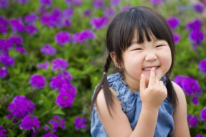 Child Smiling and Touching Her Mouth