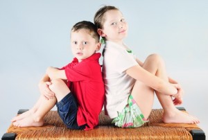 Siblings Sitting Back-to-Back