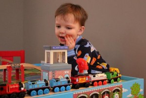 Child Playing with Toy Trains