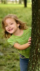 Girl playing behind tree
